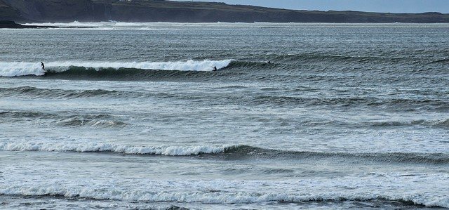 2 surfers on head high waves at Cornish Point at low tide
